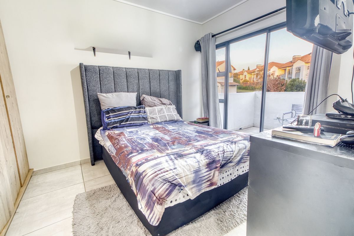 A bedroom featuring tiled flooring, a built-in wardrobe, and a sliding glass door providing access to an outdoor balcony area.