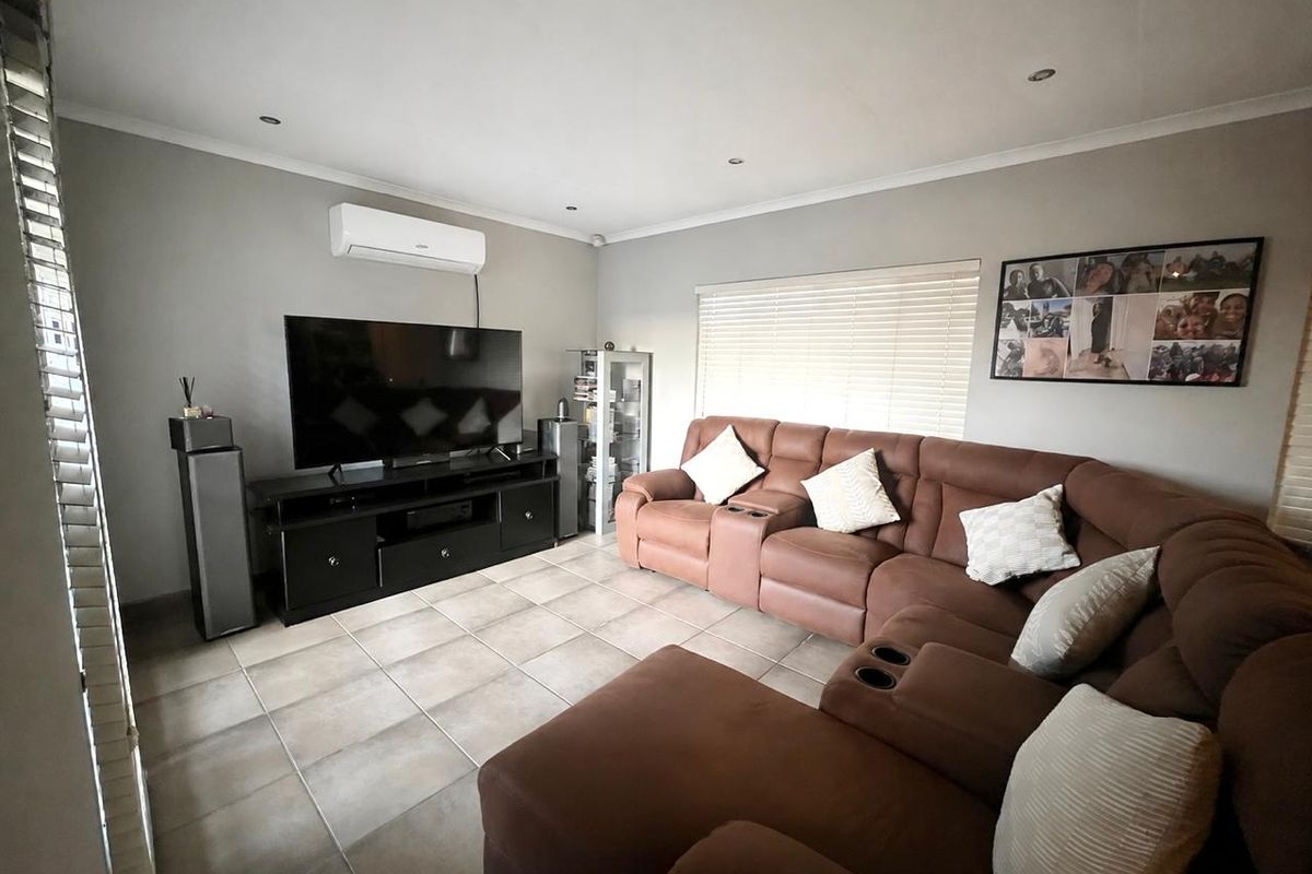 A comfortable living room featuring tiled flooring, recessed downlighting, and a wall-mounted split-system air conditioner for climate control.