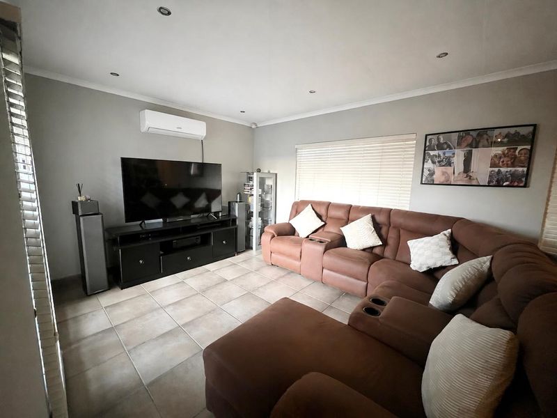 A comfortable living room featuring tiled flooring, recessed downlighting, and a wall-mounted split-system air conditioner for climate control.