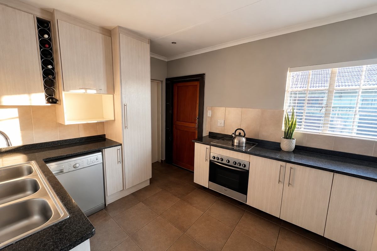 Modern kitchen featuring light wood cabinetry, granite countertops, integrated dishwasher, built-in oven, and hob with tiled flooring and ample storage space.