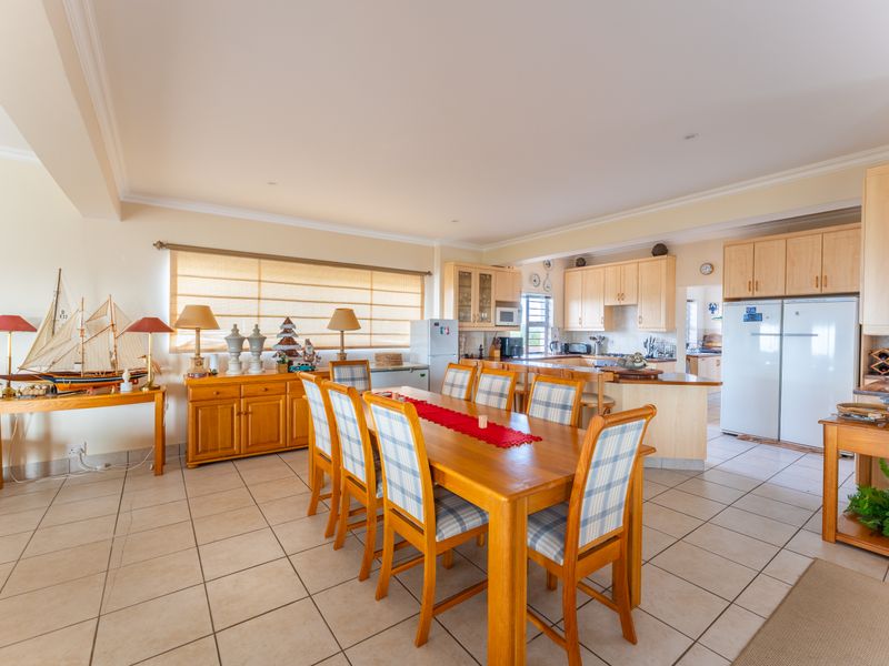 Spacious open-plan kitchen and dining area featuring tiled flooring, light wood cabinetry, and a functional kitchen island layout.