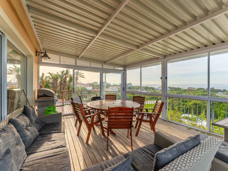 Covered outdoor patio featuring timber decking, metal balustrades, and expansive views, providing a functional space for outdoor dining and relaxation.