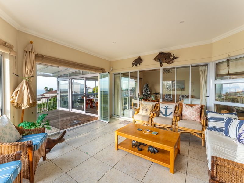 A bright, enclosed patio area featuring tiled flooring and large stacking glass doors that provide seamless access to the outdoor deck.