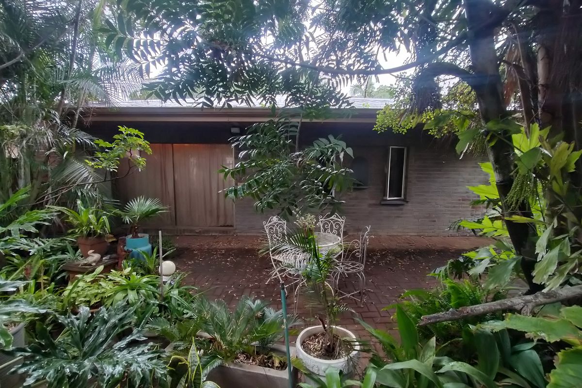 A private rear garden area featuring brick paving and a brick building facade with a sliding glass door entrance.