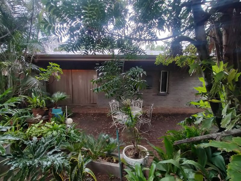 A private rear garden area featuring brick paving and a brick building facade with a sliding glass door entrance.