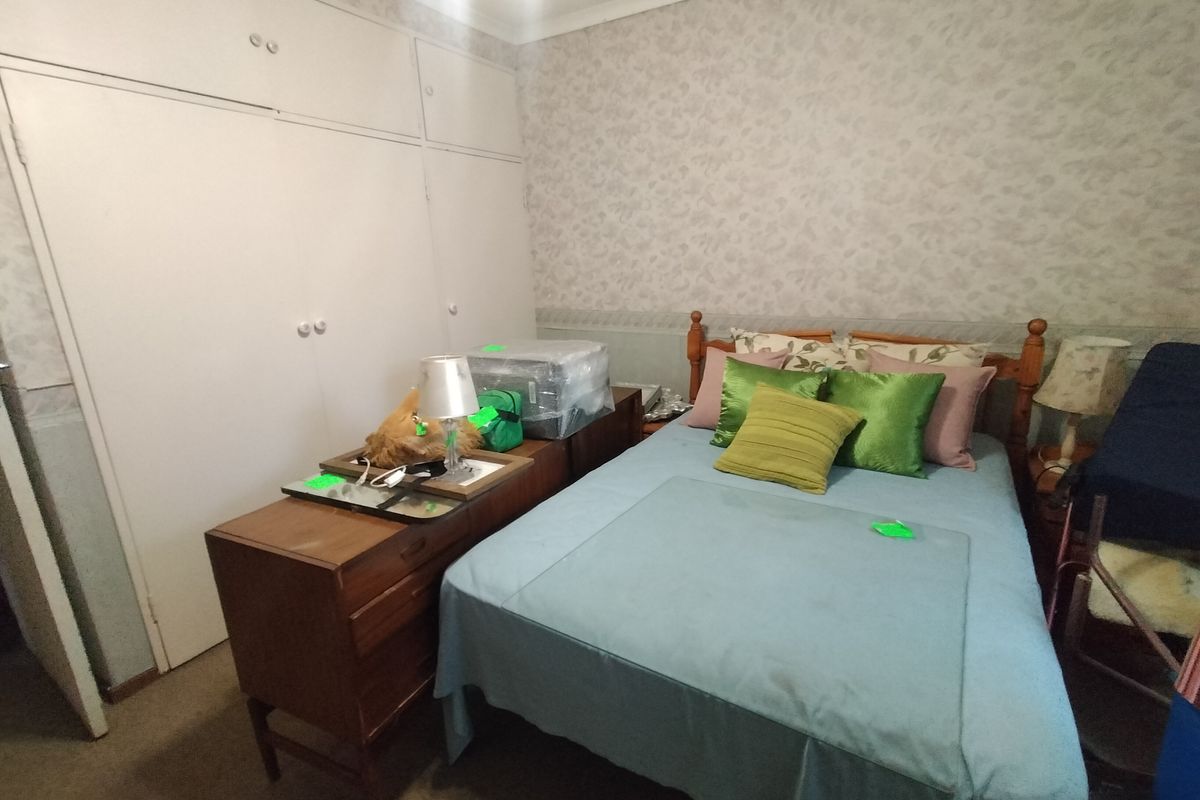 A bedroom featuring built-in wardrobes, patterned wallpaper, and carpet flooring, offering a functional space with potential for cosmetic updates.