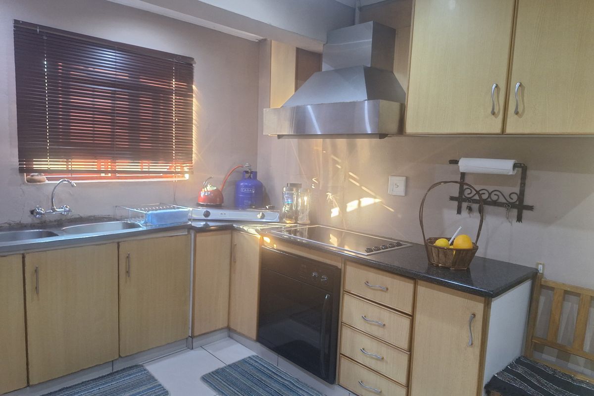 A functional kitchen featuring laminate cabinetry, granite countertops, a built-in oven with extractor fan, and tiled flooring.
