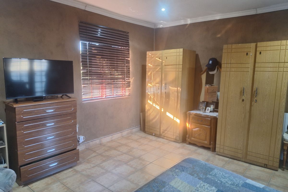 A bedroom featuring tiled flooring, venetian blinds, and recessed downlighting, providing a functional space with neutral wall finishes.