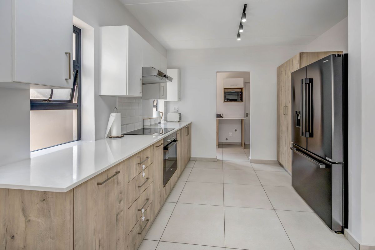 Modern kitchen featuring light wood-grain cabinetry, white quartz countertops, subway tile backsplash, and integrated appliances with a clean, contemporary aesthetic.