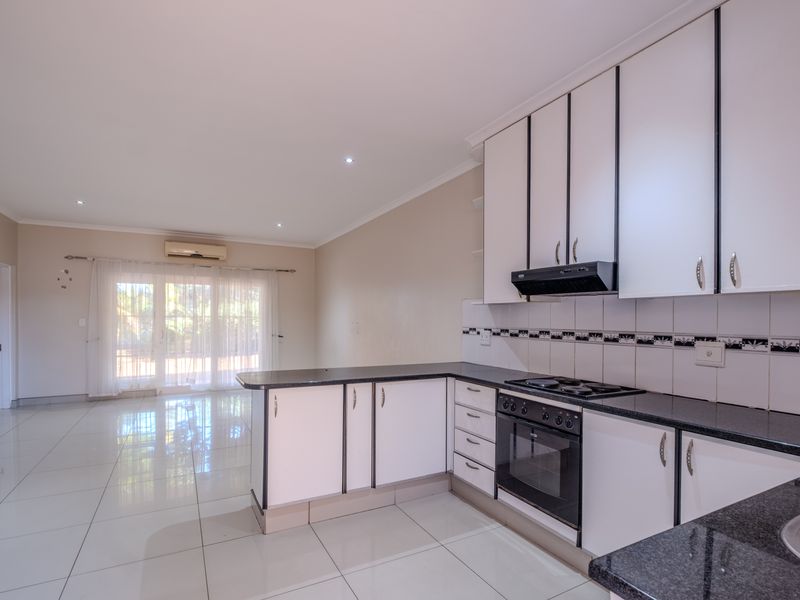 Open-plan kitchen and living area featuring tiled flooring, granite countertops, built-in cabinetry, and sliding glass doors leading to an outdoor space.
