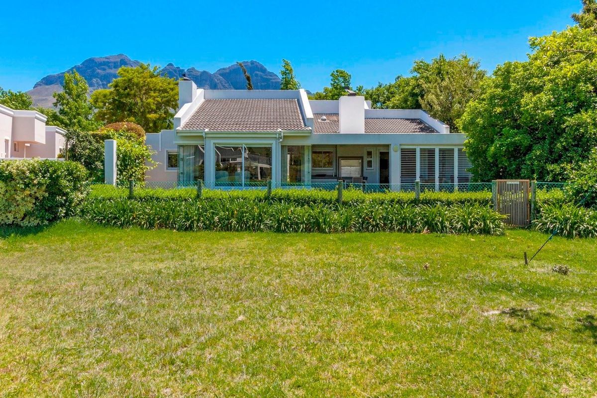 Rear view of the house featuring a tiled roof, sliding glass doors, and established garden with mountain views.