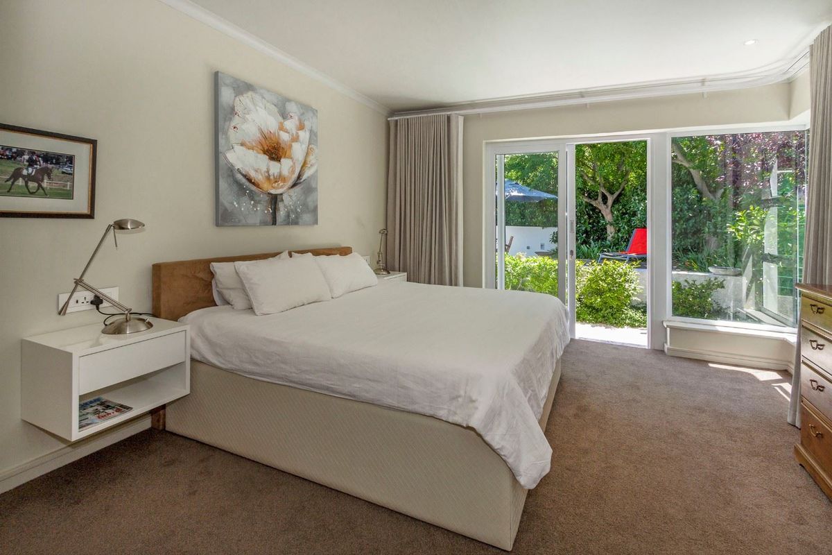 Spacious bedroom featuring neutral carpeting, recessed lighting, and large sliding glass doors providing direct access to the garden.