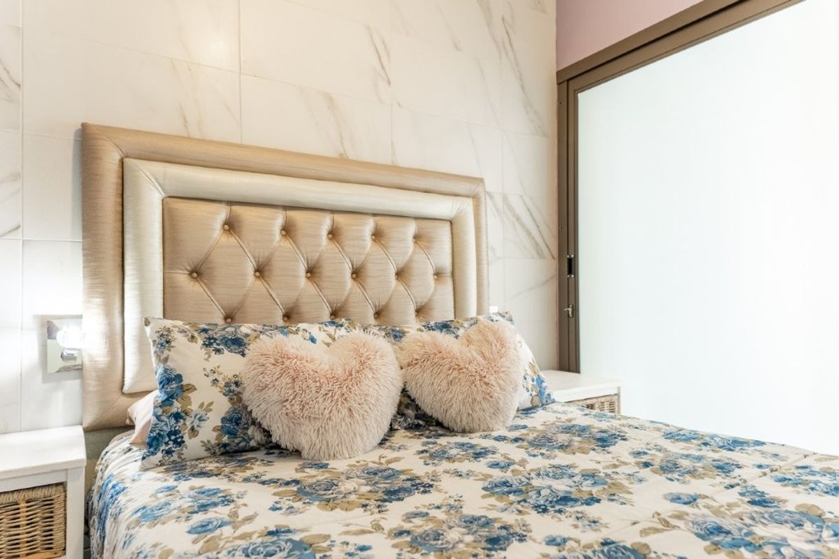 A bedroom featuring marble-look wall tiling and a sliding glass door, providing a modern and clean aesthetic.