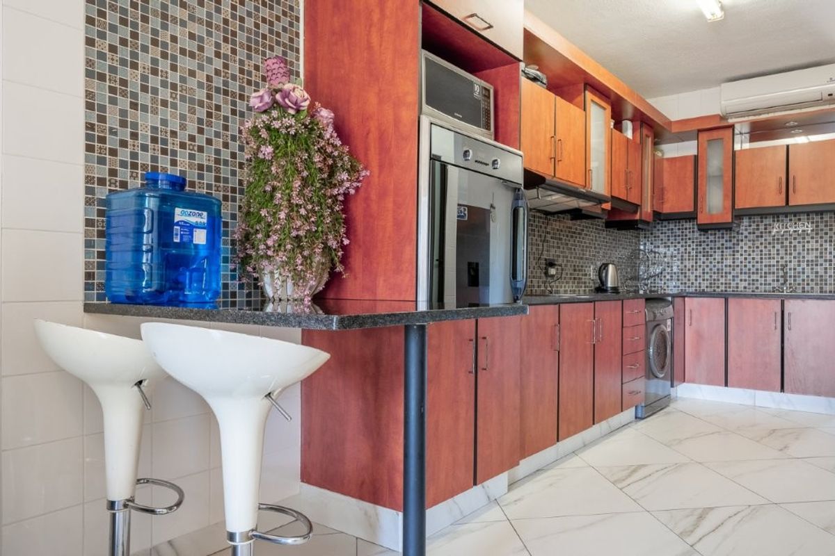 A functional kitchen featuring wood-tone cabinetry, granite countertops, a mosaic tile backsplash, and integrated appliances including an oven and microwave.