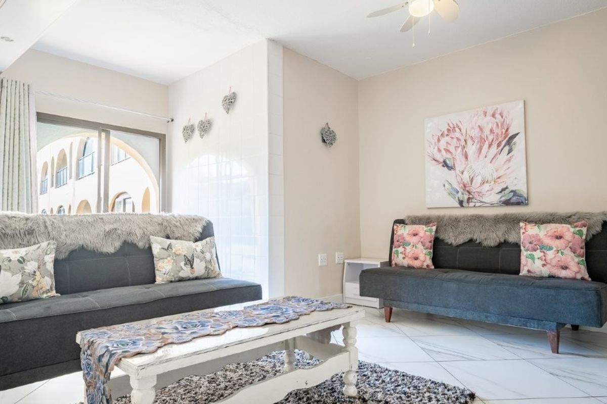 A bright living room featuring tiled flooring, a ceiling fan, and a sliding glass door providing access to an outdoor area.