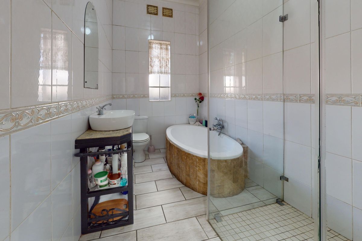 A functional bathroom featuring a freestanding bathtub, glass-enclosed shower, vessel sink, and neutral ceramic tiling throughout.