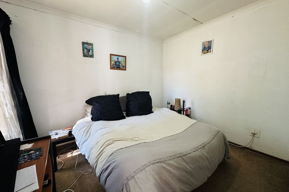 A bedroom featuring carpeted flooring and visible ceiling damage, offering a blank canvas for potential renovation and cosmetic updates.