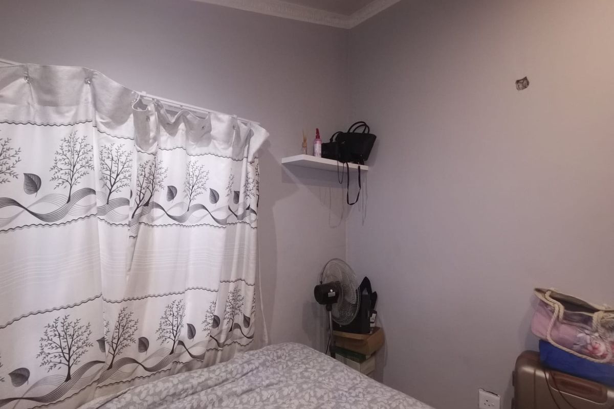 A bedroom interior featuring crown molding and a wall-mounted floating shelf, showing minor wall damage near the corner.