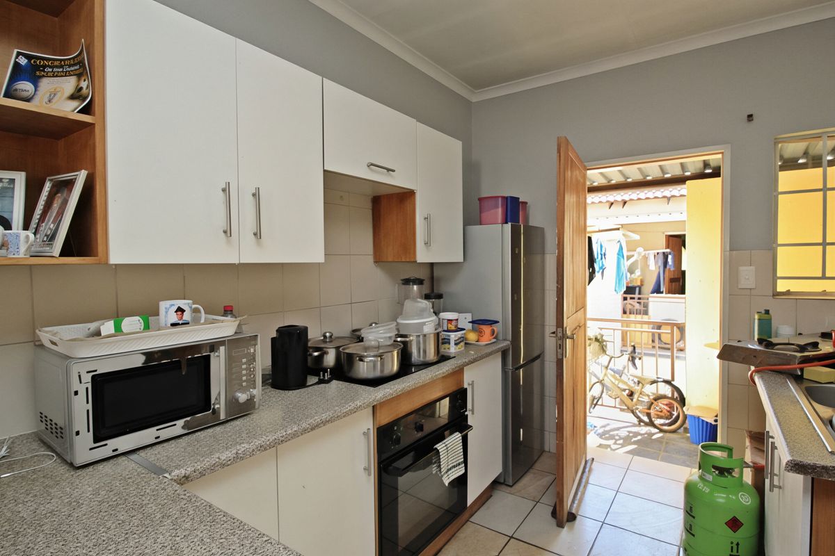 Functional kitchen featuring white cabinetry, granite countertops, tiled backsplash, and built-in oven with hob, providing direct access to an outdoor area.