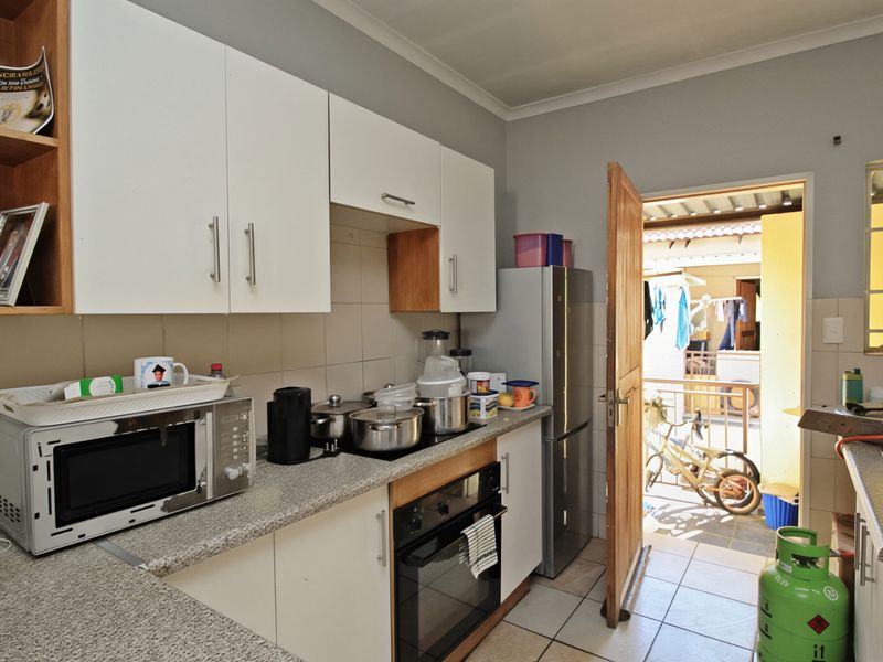 Functional kitchen featuring white cabinetry, granite countertops, tiled backsplash, and built-in oven with hob, providing direct access to an outdoor area.
