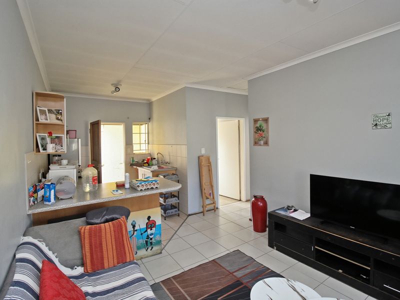 Open plan living area featuring a compact kitchen with breakfast counter and tiled flooring throughout the combined space.
