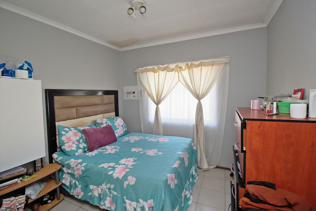 A bedroom featuring tiled flooring and a ceiling-mounted light fixture, showing a visible water stain on the ceiling requiring attention.