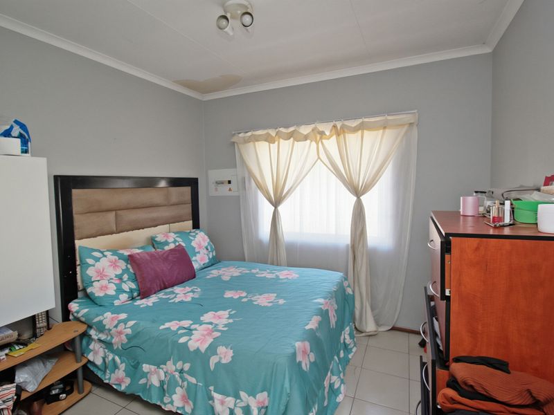 A bedroom featuring tiled flooring and a ceiling-mounted light fixture, showing a visible water stain on the ceiling requiring attention.