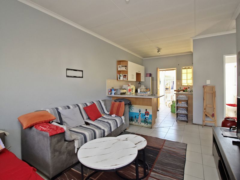 Open-plan living area featuring tiled flooring and a functional kitchen with a breakfast counter, providing a practical layout for daily living.