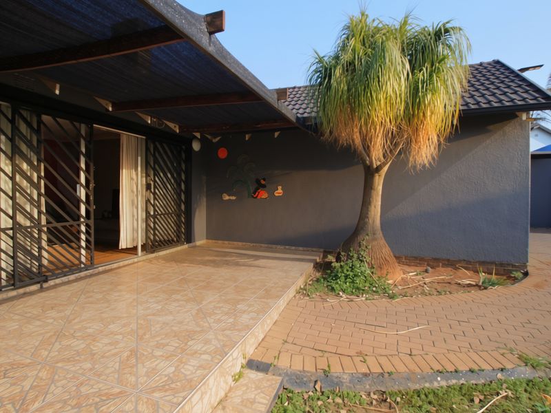 A covered patio area featuring tiled flooring, a shade cloth pergola, and direct access to the interior through a sliding glass door.