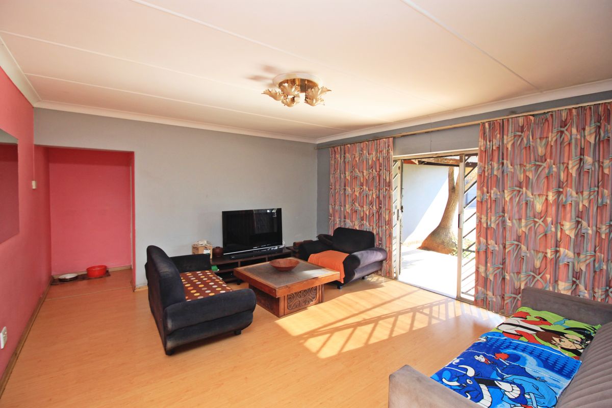 Spacious living room featuring laminate flooring, cove ceiling, and a sliding glass door providing direct access to the outdoor area.