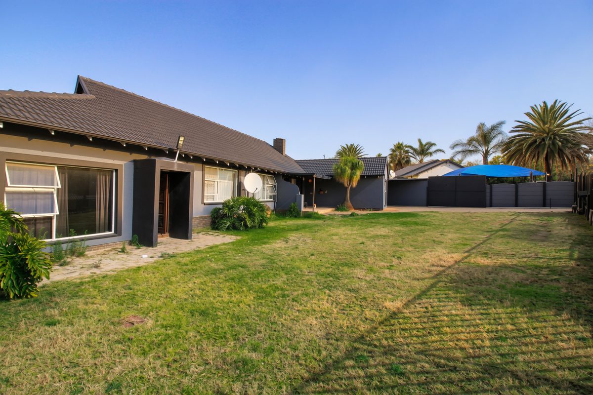 Spacious rear garden featuring a paved patio area, well-maintained lawn, and secure boundary fencing, providing a private outdoor space for the property.