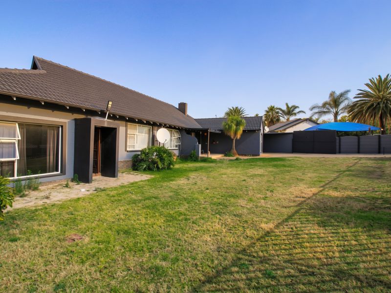 Spacious rear garden featuring a paved patio area, well-maintained lawn, and secure boundary fencing, providing a private outdoor space for the property.