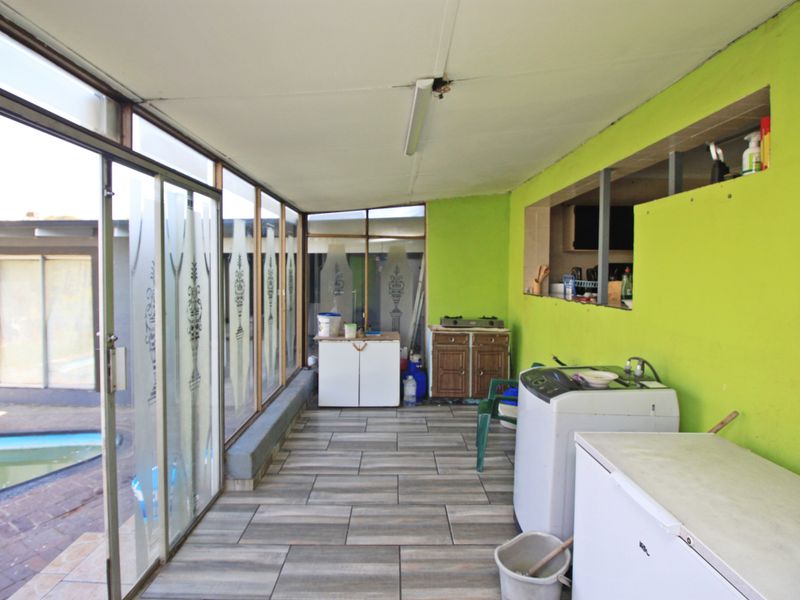 A functional laundry and utility area featuring tiled flooring, built-in cabinetry, and sliding glass doors with direct access to the outdoor pool area.