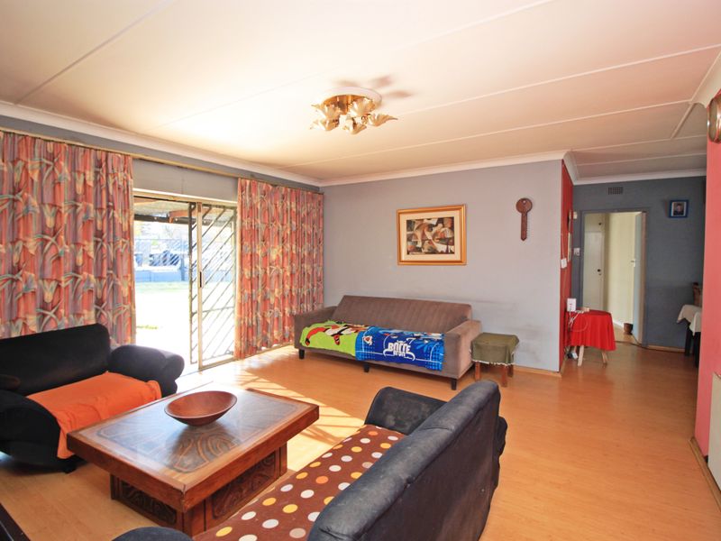 Spacious living room featuring laminate flooring, coved ceilings, and a sliding glass door providing access to the outdoor area.