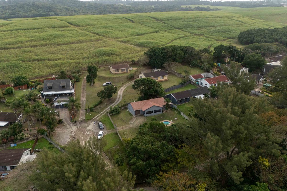 Aerial view of a residential property featuring a swimming pool, tiled roof, and surrounding garden area set within a rural landscape.