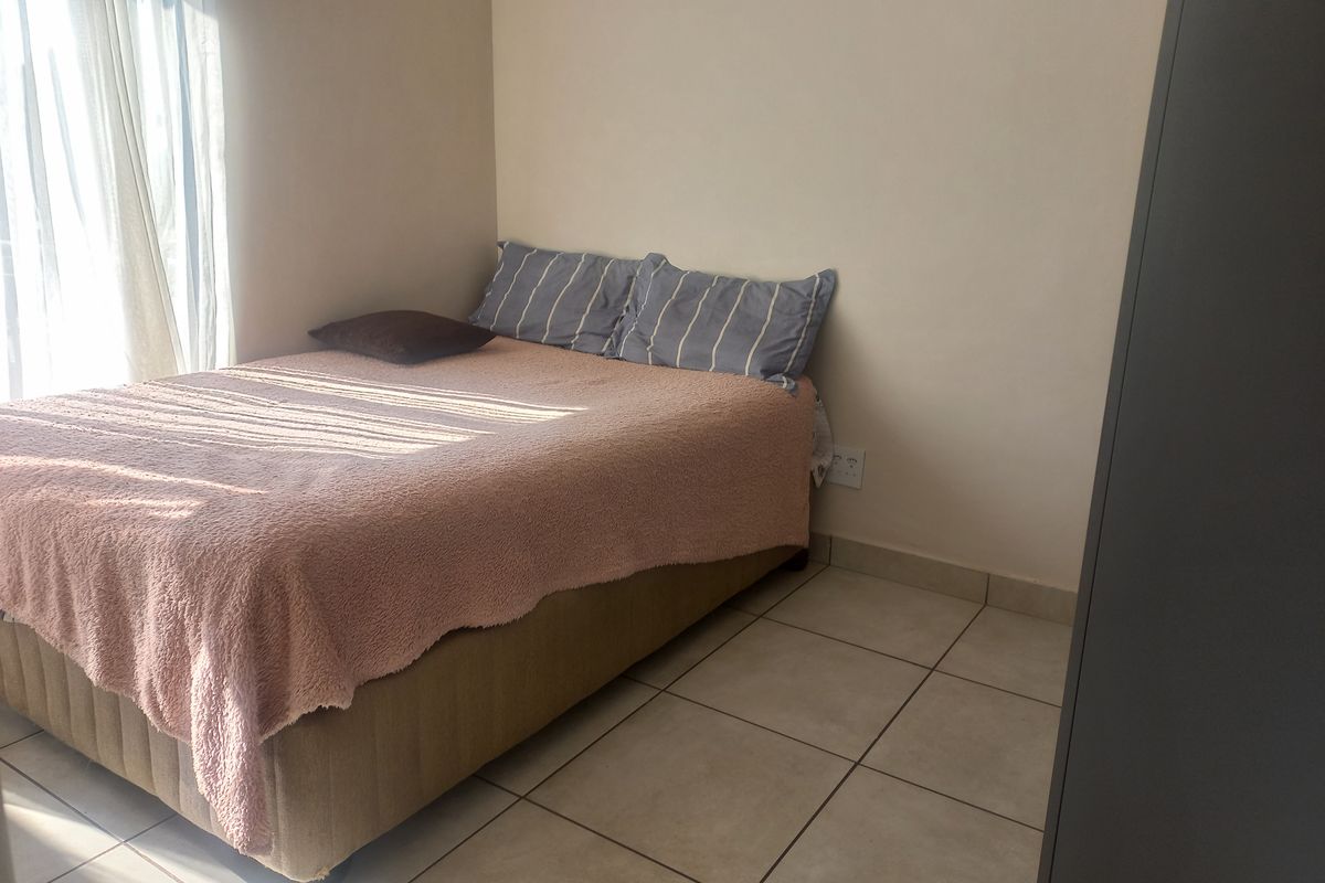 A functional bedroom featuring tiled flooring and a sliding door that allows for natural light.