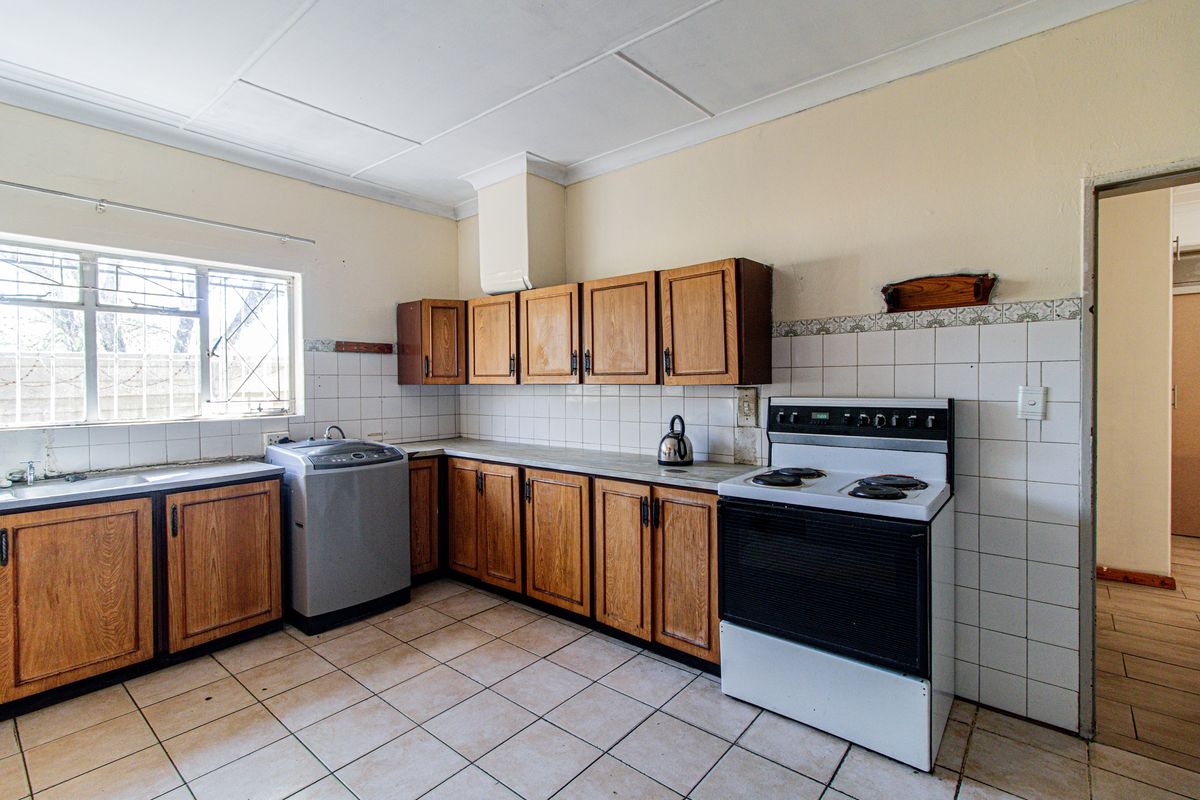 A functional kitchen featuring wooden cabinetry, tiled backsplash, and tiled flooring, offering a dated aesthetic with potential for modernization.