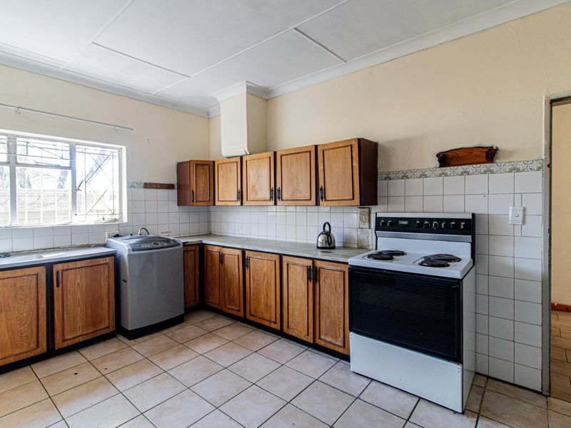A functional kitchen featuring wooden cabinetry, tiled backsplash, and tiled flooring, offering a dated aesthetic with potential for modernization.