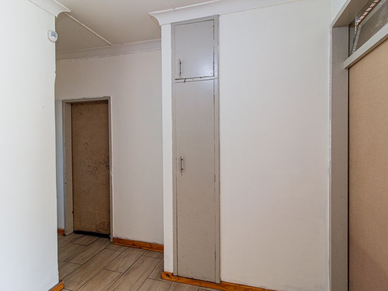 A functional hallway featuring tiled flooring, built-in storage cabinetry, and neutral wall finishes, providing access to adjacent rooms.