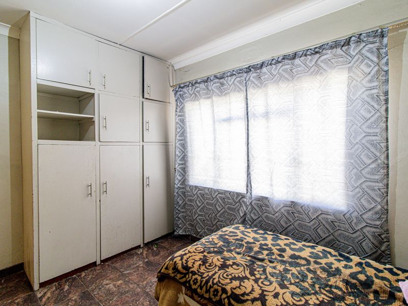 A bedroom featuring built-in cupboards and tiled flooring, offering functional storage space with potential for cosmetic updates.