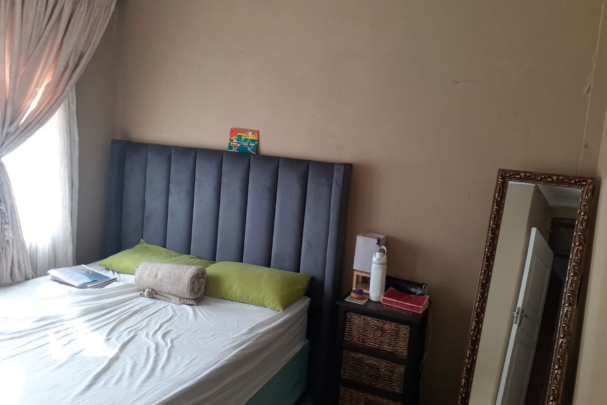 A bedroom featuring a neutral wall finish, a window with curtain track, and a standard interior door.