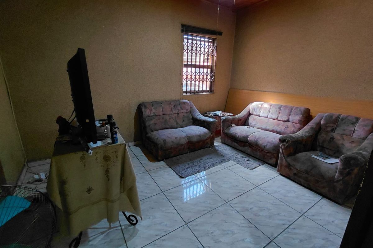 A living room featuring tiled flooring, a timber ceiling, and a window fitted with a security gate.