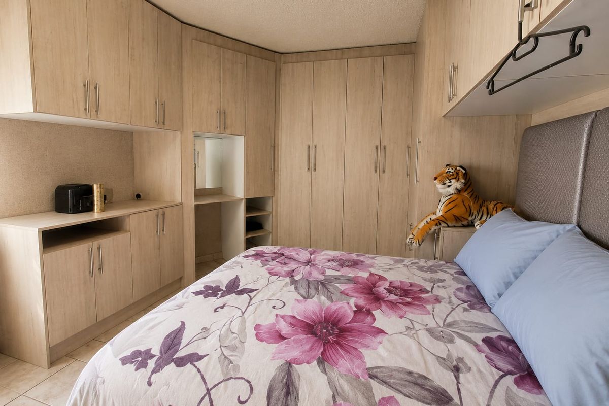 A well-maintained bedroom featuring extensive light wood-finish built-in cabinetry, integrated vanity space, and tiled flooring.