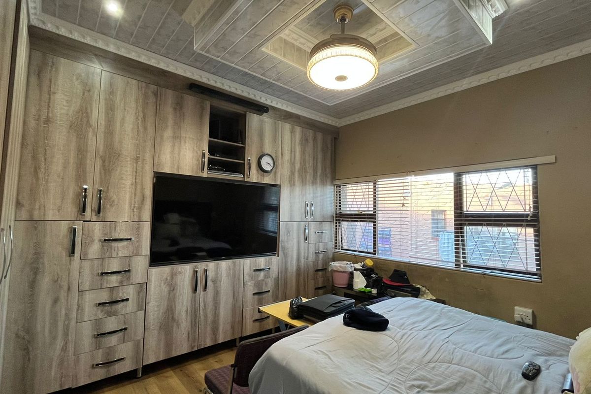 A bedroom featuring extensive built-in cabinetry, a decorative recessed ceiling with a central fan, and laminate flooring.