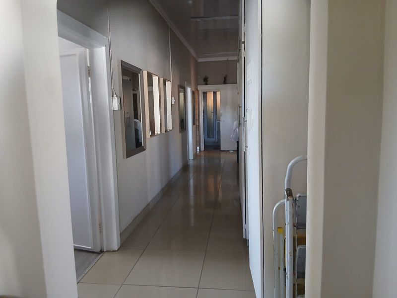 A long, tiled hallway featuring built-in storage cupboards and access to multiple rooms.