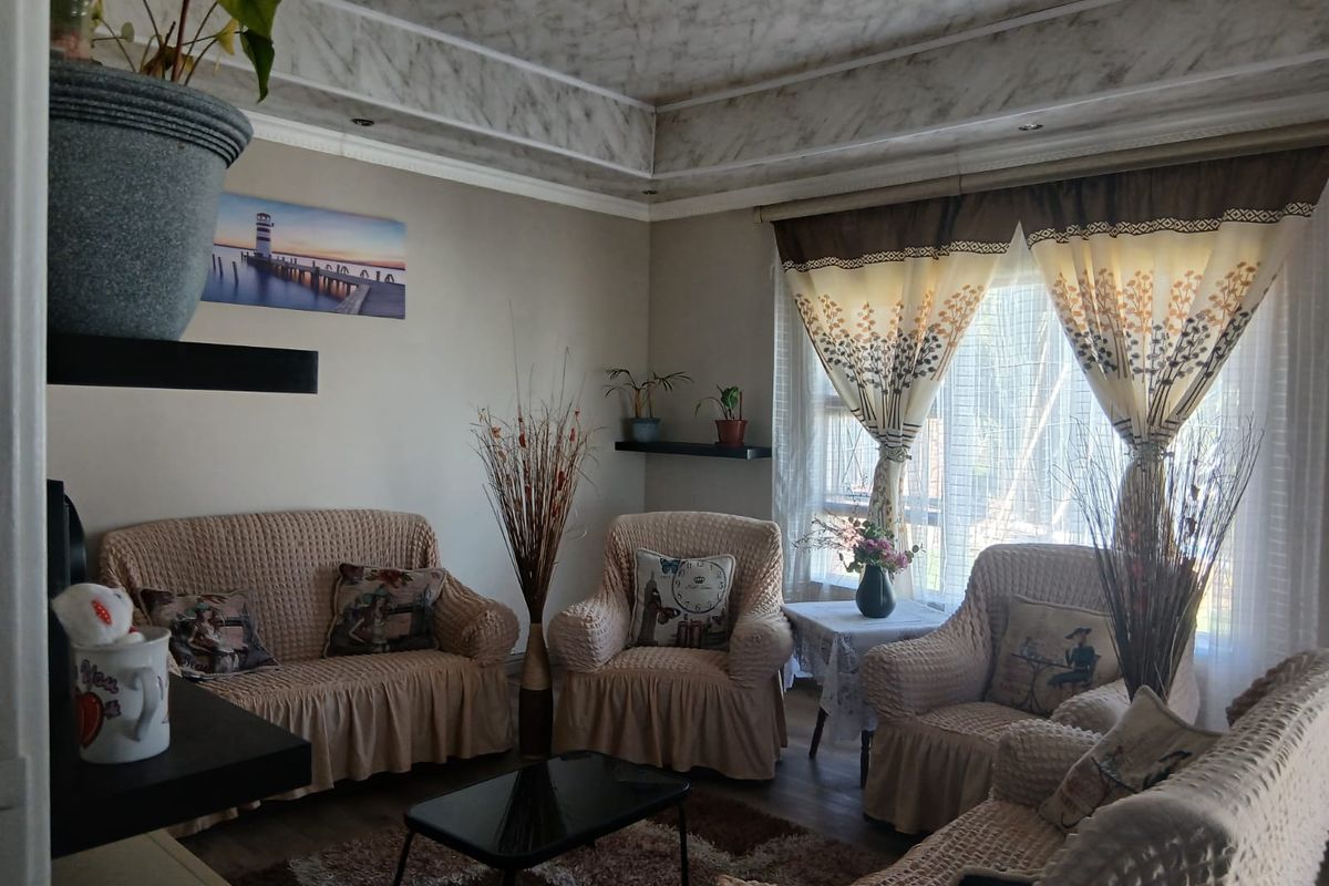 A cozy living room featuring a decorative recessed ceiling with molding and a large window allowing natural light into the space.