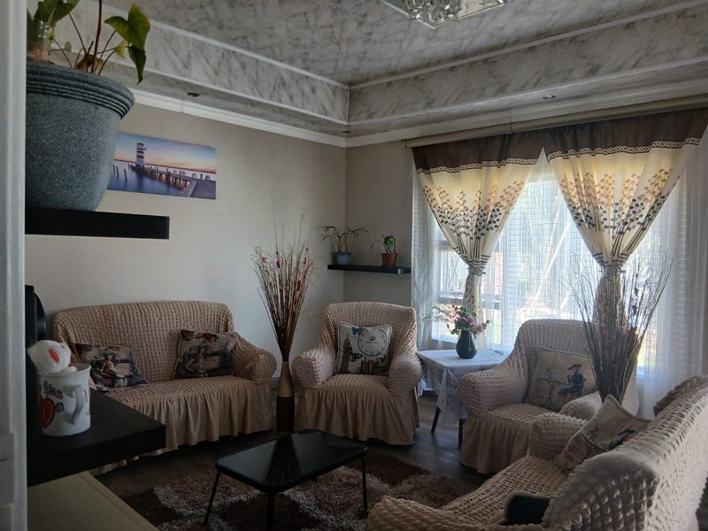 A cozy living room featuring a decorative recessed ceiling with molding and a large window allowing natural light into the space.