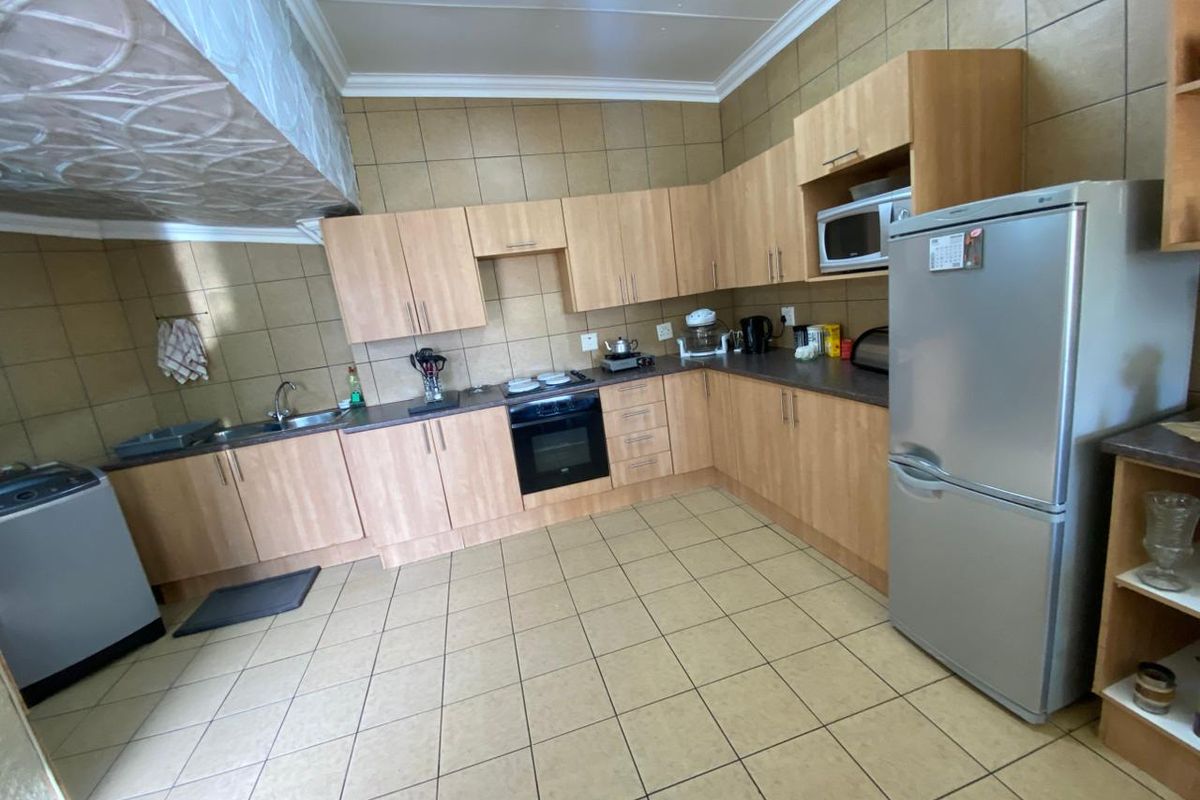 Functional kitchen featuring light wood-tone cabinetry, tiled backsplash, built-in oven and hob, and tiled flooring throughout.