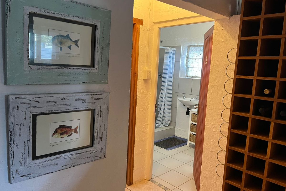 A view through a doorway into a functional bathroom featuring tiled floors and a shower, adjacent to a built-in wine storage unit.