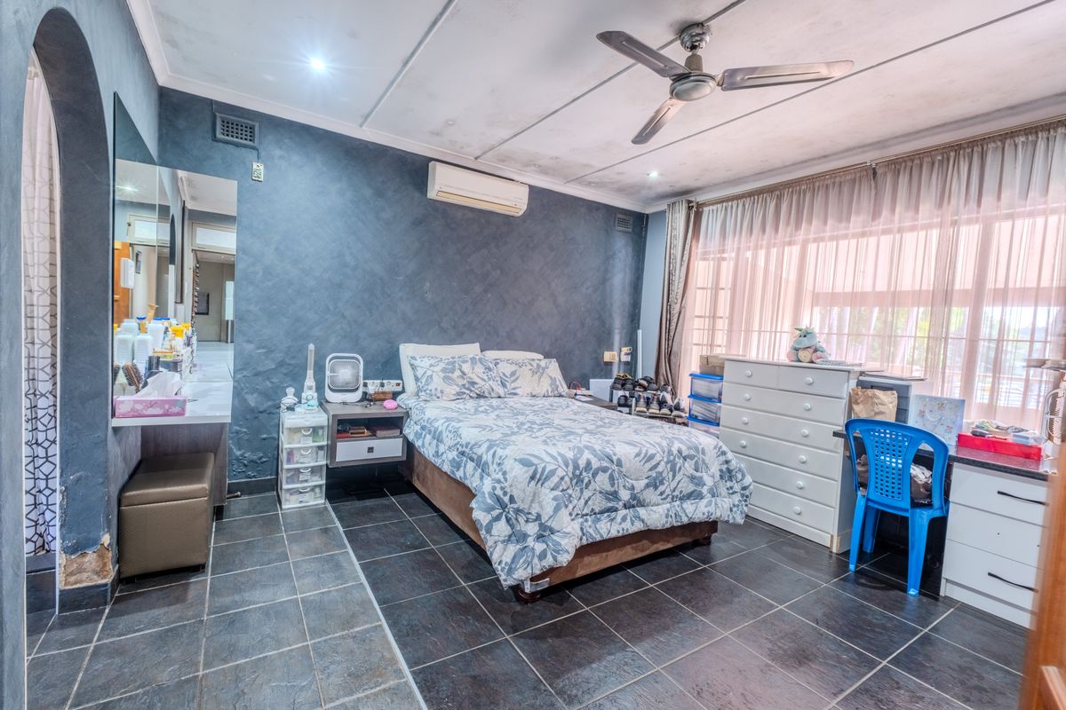 A bedroom featuring dark tiled flooring, a ceiling fan, split-system air conditioning, and a built-in vanity area with an arched entryway.